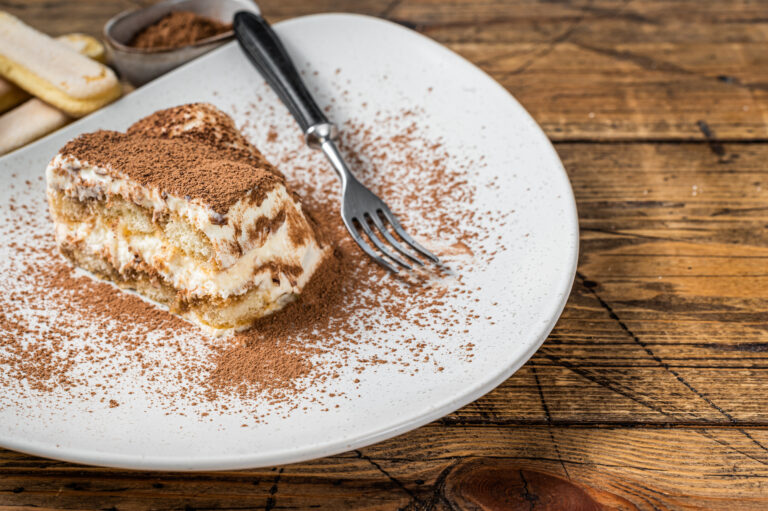 Tiramisu Italian cake with cocoa in a plate. Wooden background